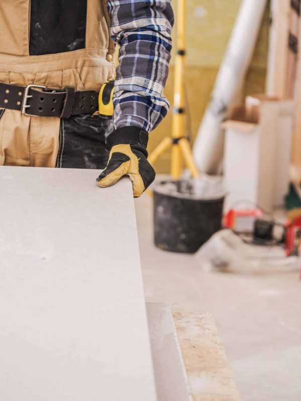 male-contractor-holding-piece-of-drywall-material